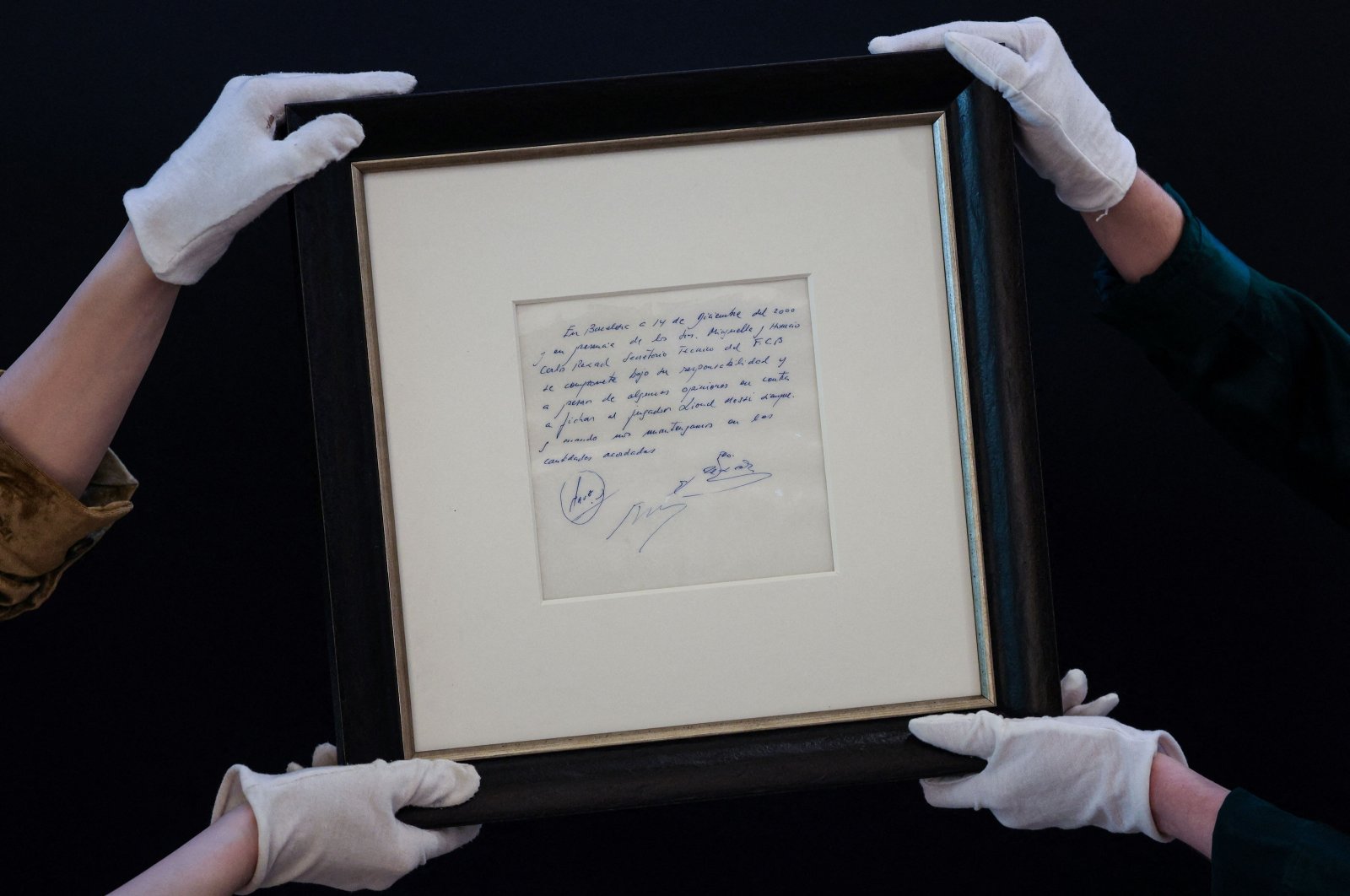 Members of staff show the napkin on which the 13-year-old Argentinian football player Lionel Messi was promised his first contract with FC Barcelona, during a photocall at Bonhams, London, U.K., May 8, 2024. (AFP Photo)