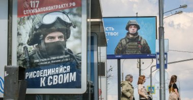 People stand at a bus stop next to an advertisement for military conscription in Moscow, Russia, May 21, 2024. (EPA Photo)