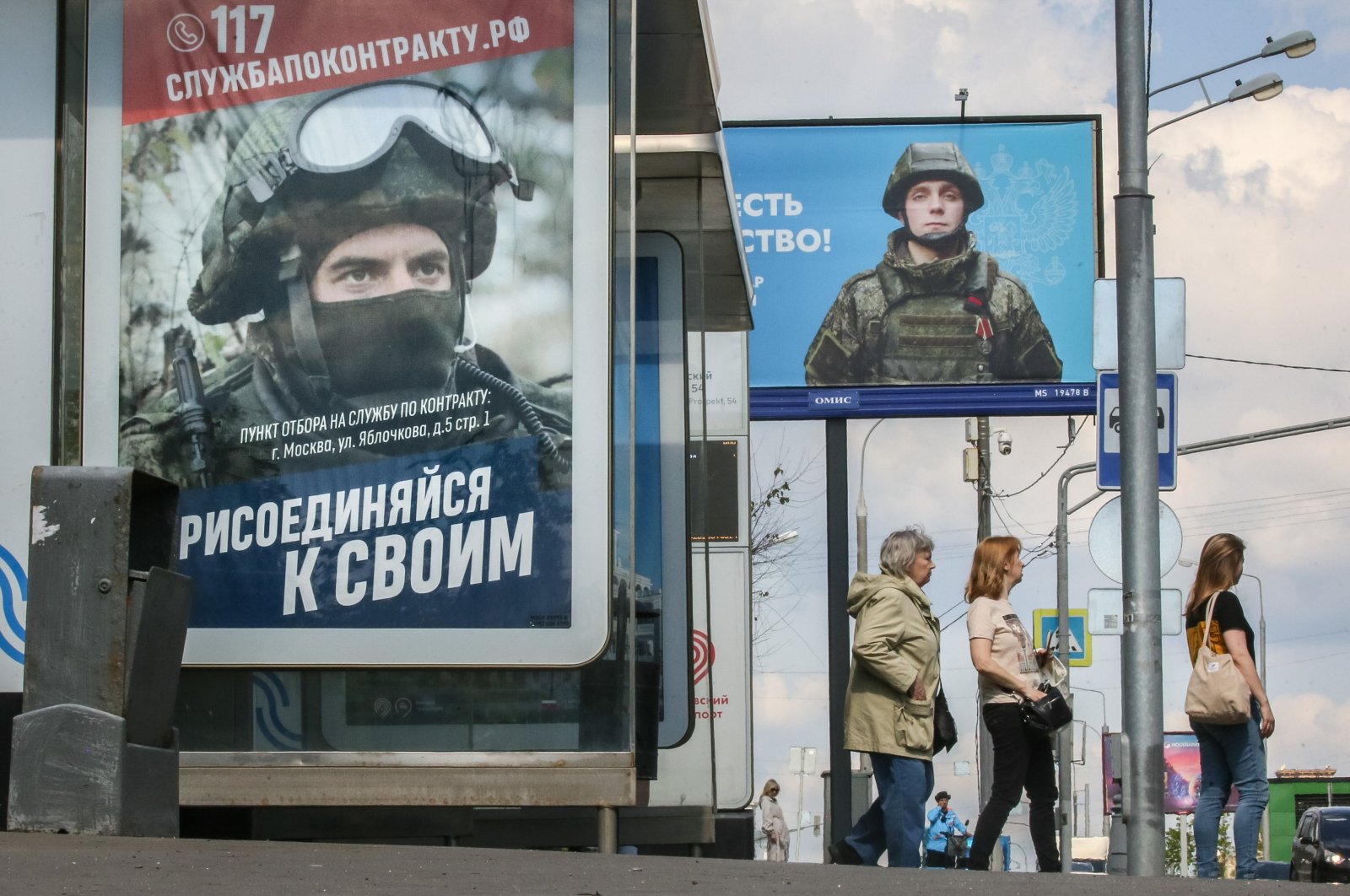 People stand at a bus stop next to an advertisement for military conscription in Moscow, Russia, May 21, 2024. (EPA Photo)