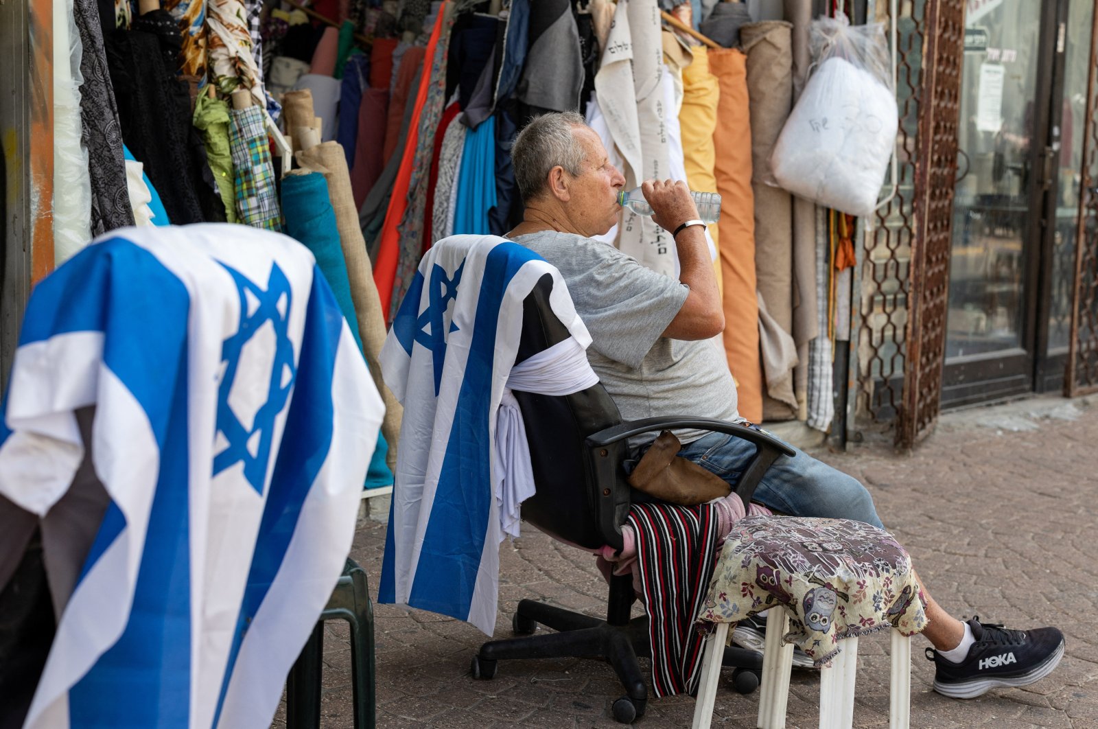 A man drinks water as he sits on an office chair with an Israeli flag placed on it, in Tel Aviv, Israel, May 21, 2024. (Reuters Photo)