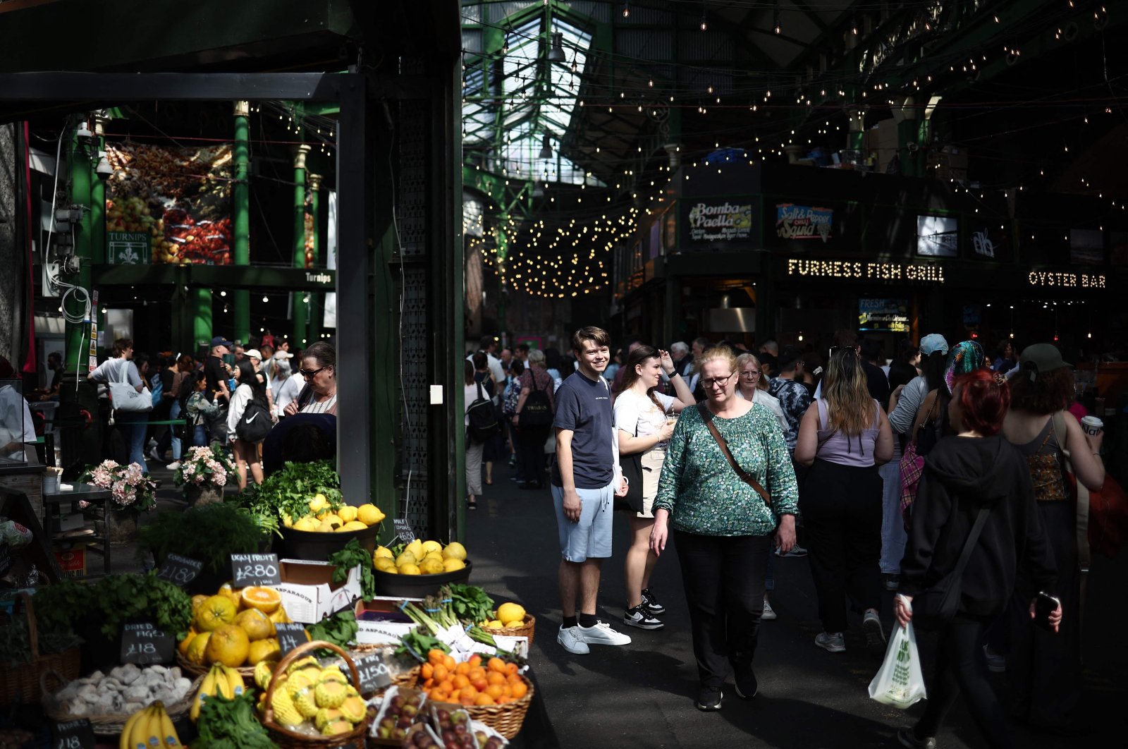 People walk past fruit and vegetable stalls at Borough Market, London, U.K., May 10, 2024. (AFP Photo)