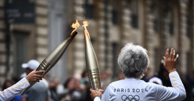 Two torch bearers relay each other during the Olympic and Paralympic Torch Relays, ahead of the Paris 2024 Olympic and Paralympic Games, Bordeaux, France, May 23, 2024. (AFP Photo)