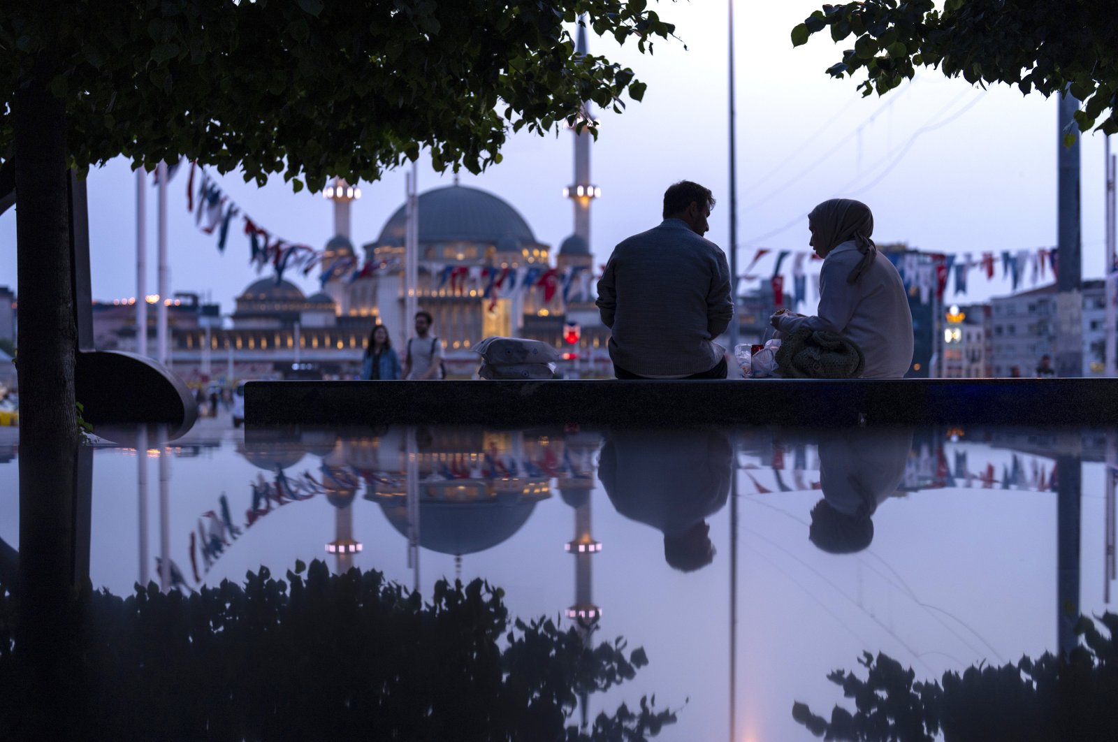 A couple sit in a public bench at Taksim square in Istanbul, Türkiye, May 22, 2024. (AP Photo)