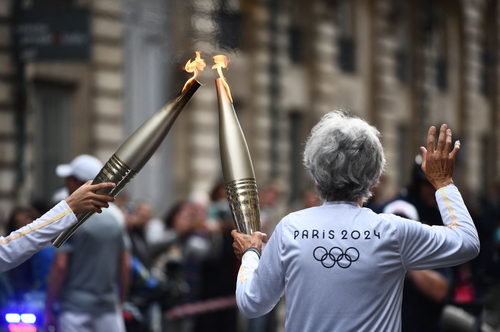 Two torch bearers relay each other during the Olympic and Paralympic Torch Relays, ahead of the Paris 2024 Olympic and Paralympic Games, Bordeaux, France, May 23, 2024. (AFP Photo)