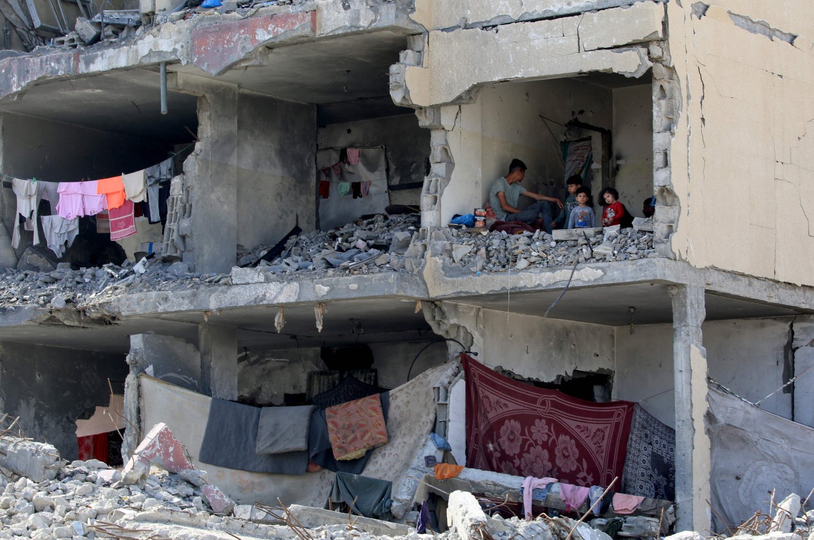  A Palestinian man and his children sit in a destroyed room following the targeting of a residential building by an Israeli airstrike in Rafah in the southern Gaza Strip, May 22, 2024. (AFP Photo)