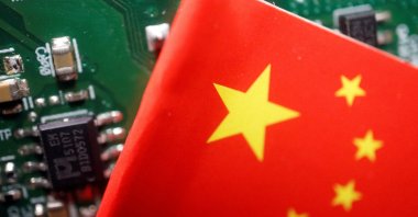 A Chinese flag is displayed next to a &quot;Made in China&quot; sign seen on a printed circuit board with semiconductor chips, in this illustration picture taken Feb. 17, 2023. (Reuters Photo)