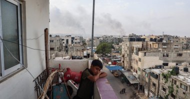A boy stands on a balcony with a view of billowing smoke from Israeli strikes in Rafah city, southern Gaza Strip, Palestine, May 28, 2024. (AFP Photo)