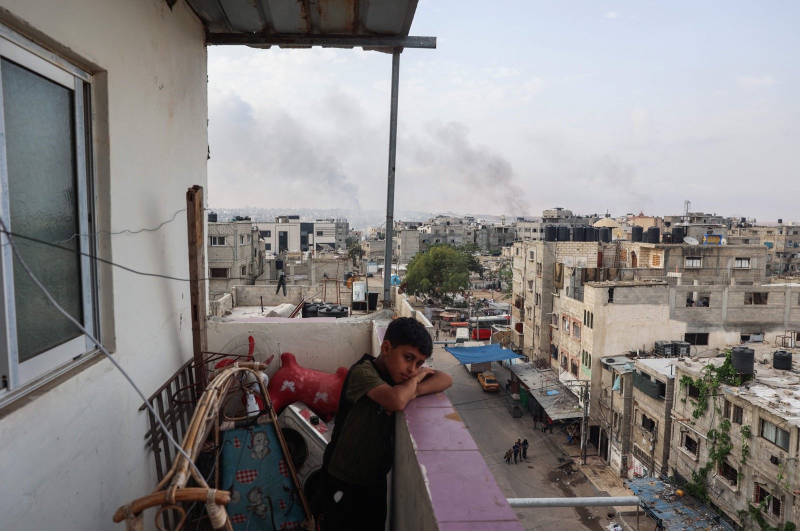 A boy stands on a balcony with a view of billowing smoke from Israeli strikes in Rafah city, southern Gaza Strip, Palestine, May 28, 2024. (AFP Photo)
