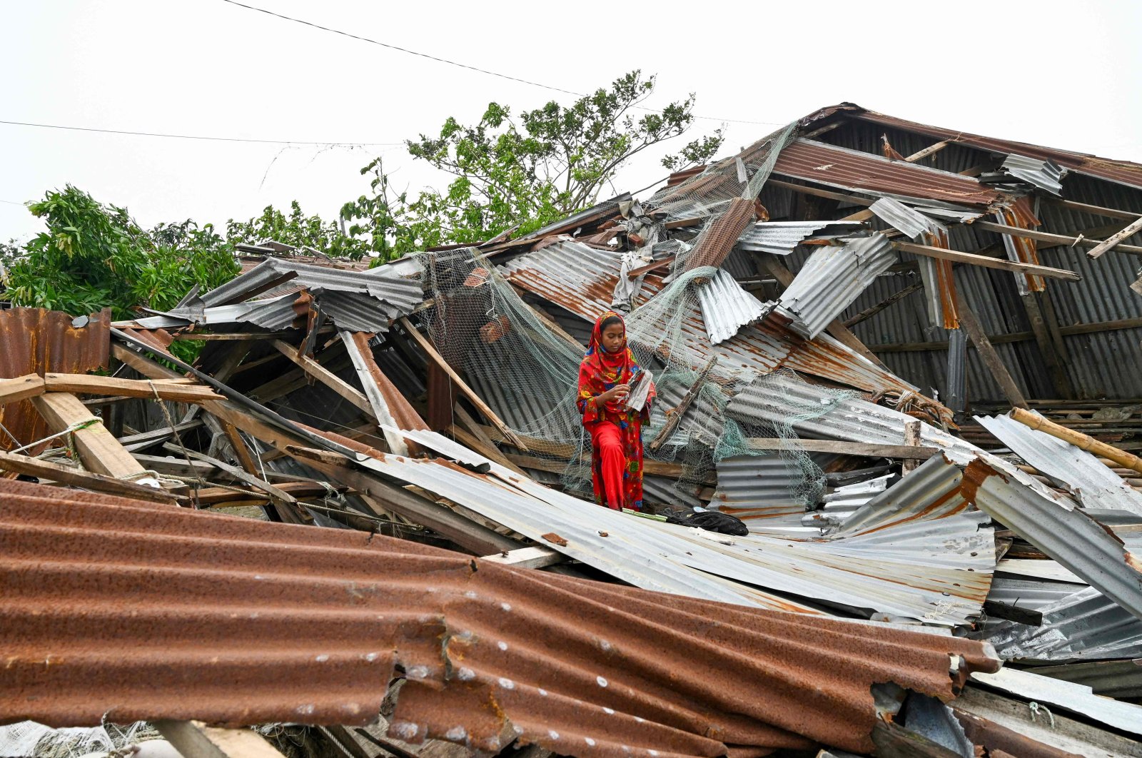 A girl walks amid her damaged house after cyclone Remal&#039;s landfall in Patuakhalim Bangladesh, May 28, 2024. (AFP Photo)