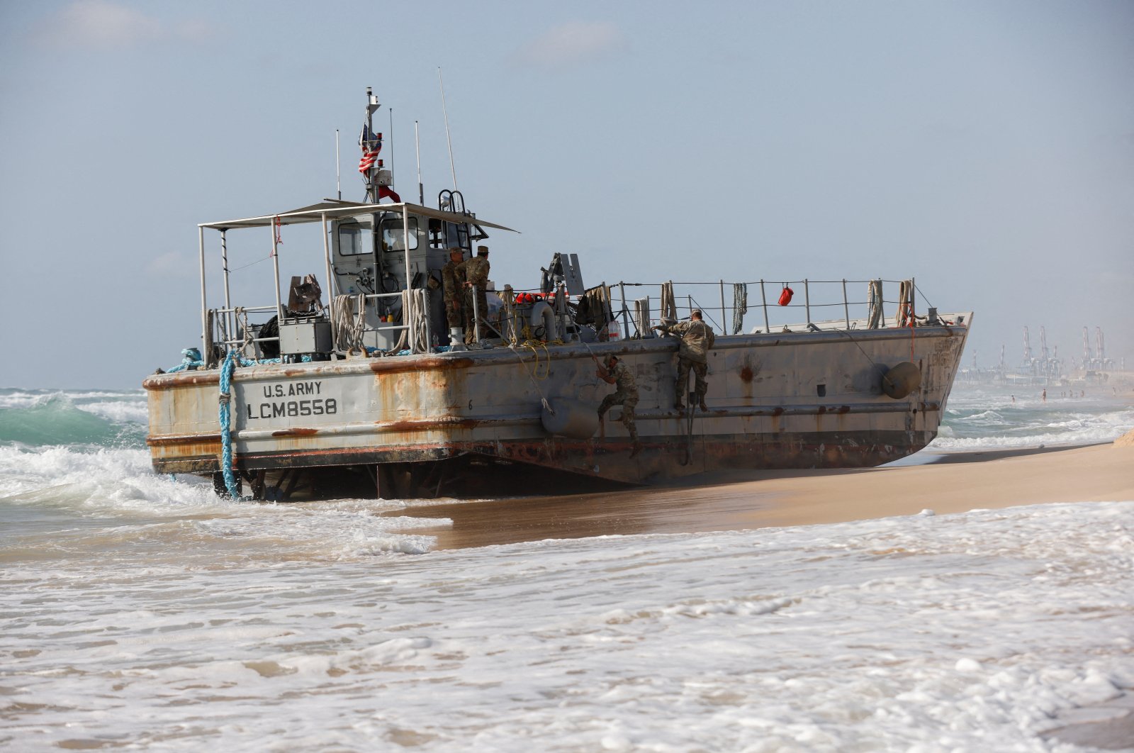 U.S. troops climb a beached vessel used for delivering aid to Palestinians via a new U.S.-built pier in Gaza, after it ran aground along with another aid vessel, on the Mediterranean shore in Ashdod, May 25, 2024. (Reuters Photo)