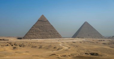 Tourists ride camels past the Great Pyramid of Khufu (Cheops, R) and the Pyramid of Khafre (Chephren, L) at the Giza Pyramids Necropolis on the outskirts of Giza, Egypt, May 3, 2024. (AFP Photo)