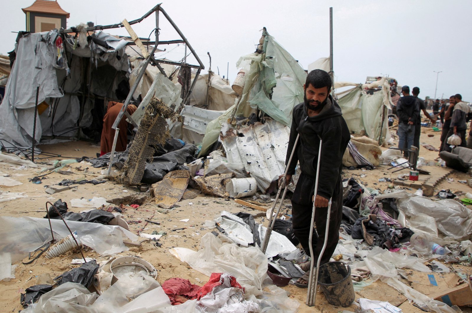 A man looks on as Palestinians inspect a tent camp damaged in an Israeli strike in Rafah, southern Gaza Strip, Palestine, May 28, 2024. (Reuters Photo)