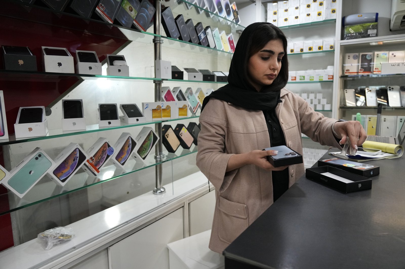 A cellphone vendor works at her shop in downtown Tehran, Iran, Feb. 21, 2024. (AP Photo)