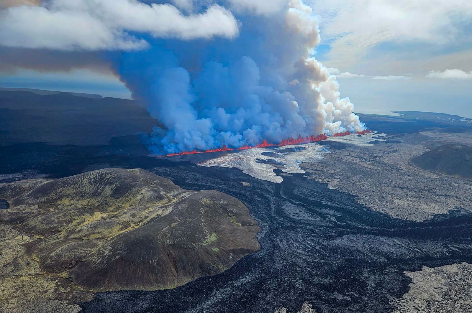  This handout picture released by the Icelandic Coast Guard shows billowing smoke and flowing lava pouring out of a new fissure, during a surveilance flight above a new volcanic eruption on the outskirts of the evacuated town of Grindavik, western Iceland, May 29, 2024. (AFP Photo)