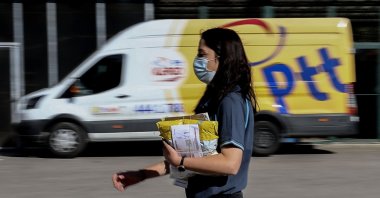 A PTT employee walks in front of a postal service vehicle in Turkish capital Ankara&#039;s Yenimahalle district, Ankara, Türkiye, Oct. 9, 2021. (AA Photo)