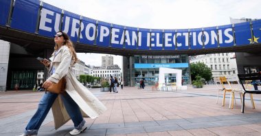 A pedestrian walks past a banner displayed on the building of the European Parliament in Brussels ahead of the European elections, Belgium, May 17, 2024. (AFP Photo)