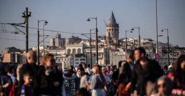 People walk on the Galata Bridge, with the Galata Tower seen in the background, June 3, 2024. (Reuters Photo)