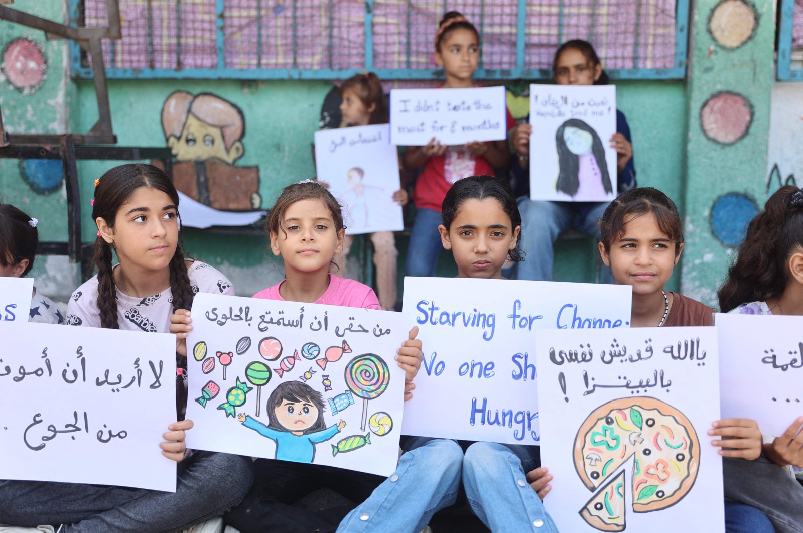 Children hold signs at a U.N. school housing displaced Palestinians in Gaza City on June 4, 2024. (AFP Photo)