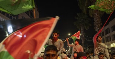 Former Palestinian prisoners, who were released by the Israeli authorities, fly Palestinian and Hamas flags while they are carried on the shoulders upon their arrival in the West Bank town of Beitunia, Friday, Nov. 24, 2023. (AP Photo)