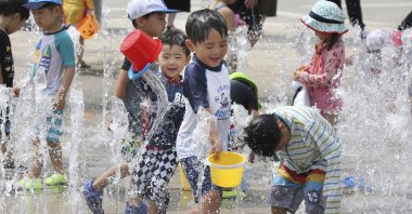 Children play in the water to cool off at a park in Yokohama, near Tokyo, Aug. 18, 2020. (AP Photo)