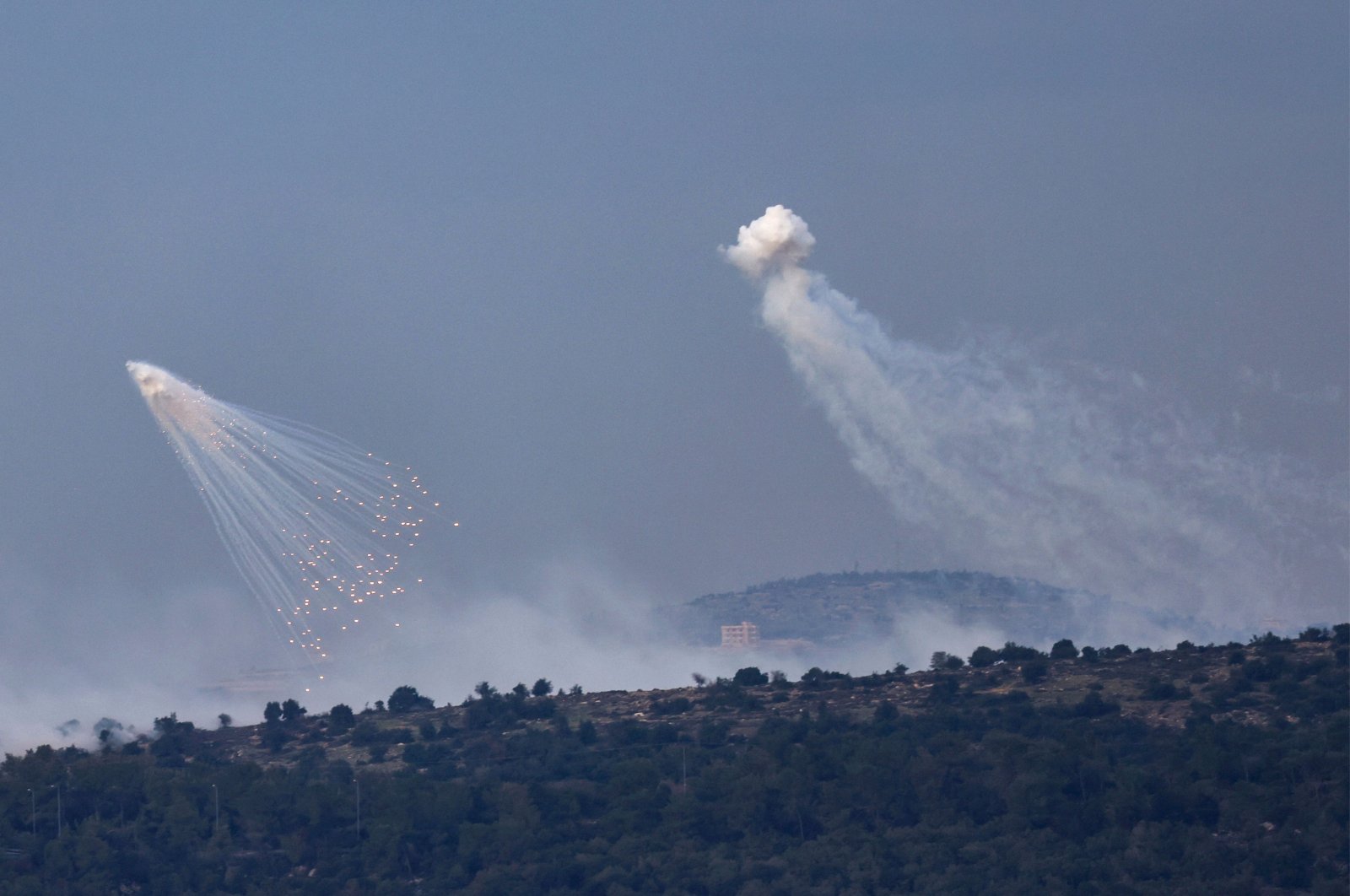 A picture taken from the Israeli side of the border with Lebanon shows shells exploding over hills around the southern Lebanese village of Aita al-Shaab, Dec. 8, 2023. (AFP Photo)