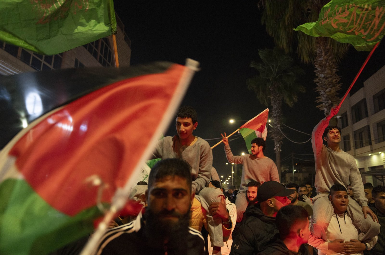 Former Palestinian prisoners, who were released by the Israeli authorities, fly Palestinian and Hamas flags while they are carried on the shoulders upon their arrival in the West Bank town of Beitunia, Friday, Nov. 24, 2023. (AP Photo)