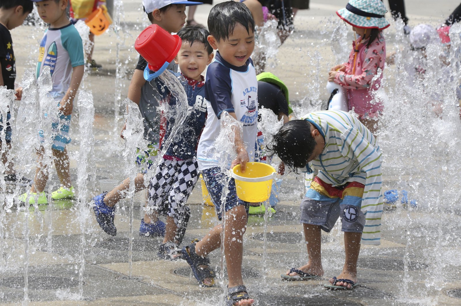 Children play in the water to cool off at a park in Yokohama, near Tokyo, Aug. 18, 2020. (AP Photo)