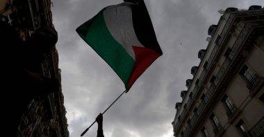 A protestor holds up a Palestinian flag during a demonstration called by the French organization &quot;France Palestine Solidarite&quot; to protest an overnight Israeli strike on a camp in Rafah for internally displaced Palestinians, Paris, France, May 27, 2024. (AFP Photo)