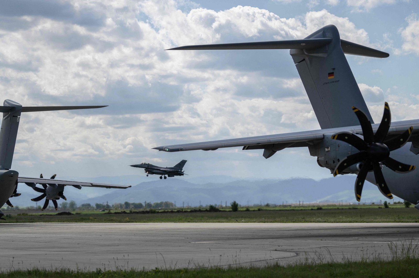 A Romanian Air Force F-16 (C) is pictured between Spanish and German military cargo planes at 71 Aerial Base Campia Turzii, Romania, May 14, 2024. (AFP Photo)