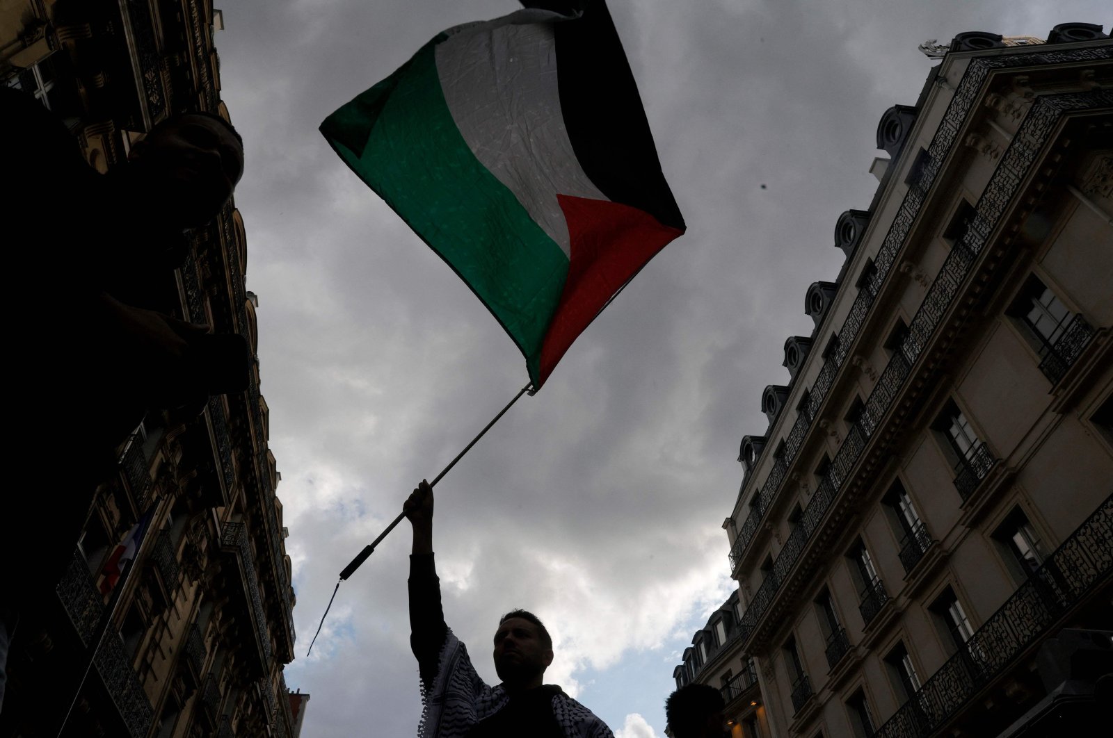 A protestor holds up a Palestinian flag during a demonstration called by the French organization "France Palestine Solidarite" to protest an overnight Israeli strike on a camp in Rafah for internally displaced Palestinians, Paris, France, May 27, 2024. (AFP Photo)