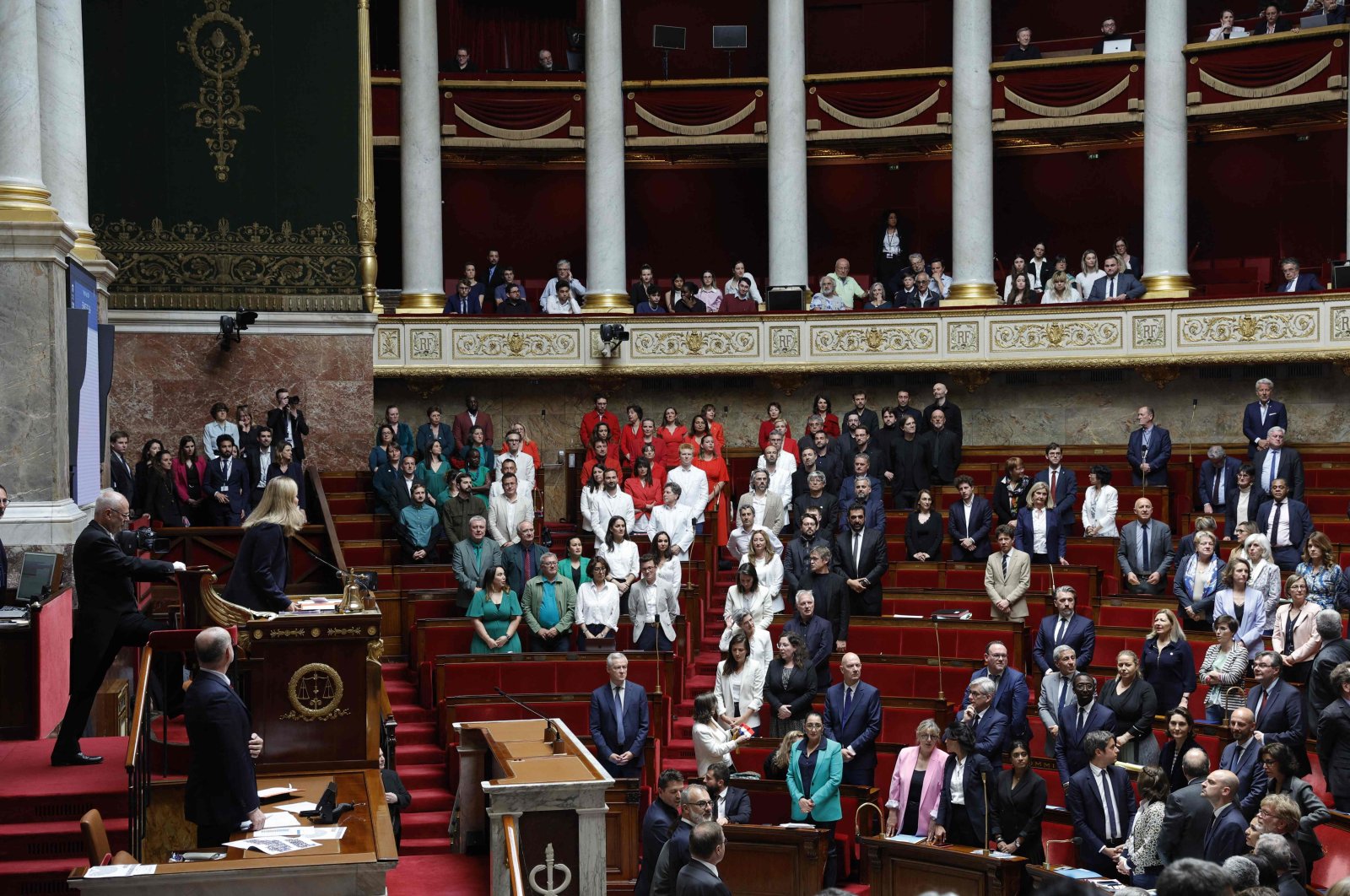  French members of Parliament stand during a session of questions to the government at the National Assembly, after French Member of Parliament of &quot;La France Insoumise&quot; (LFI) group Rachel Keke waved a Palestinian flag in the Assembly Chamber in Paris on June 4, 2024. (AFP Photo)