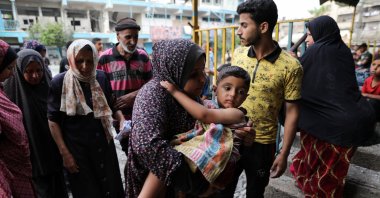 A woman carries a child at the site of an Israeli strike on a UNRWA school sheltering displaced people in Nuseirat refugee camp, amid the Israeli attacks on Gaza, Gaza Strip, Palestine, June 6, 2024. (Reuters Photo)