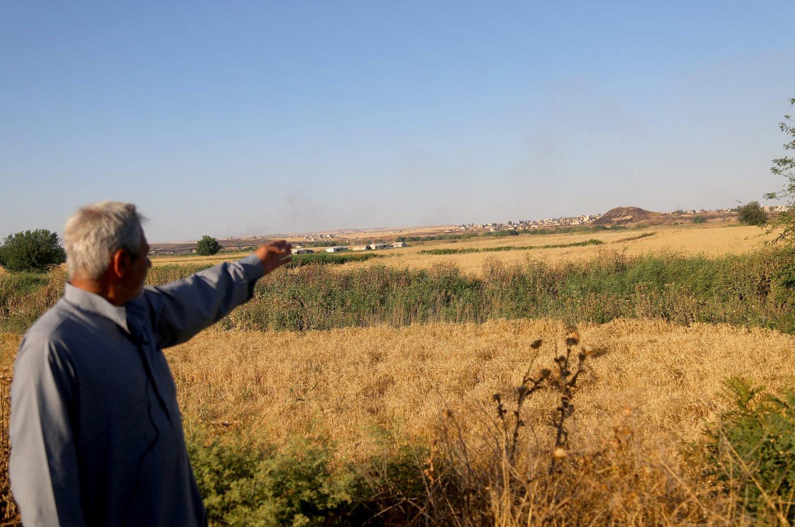 Shavvak Assaf, who had to migrate from Shuyuk village, gestures at the town of Manbij in the distance during an interview with Anadolu Agency (AA), northern Syria, April 13, 2024. (AA Photo)