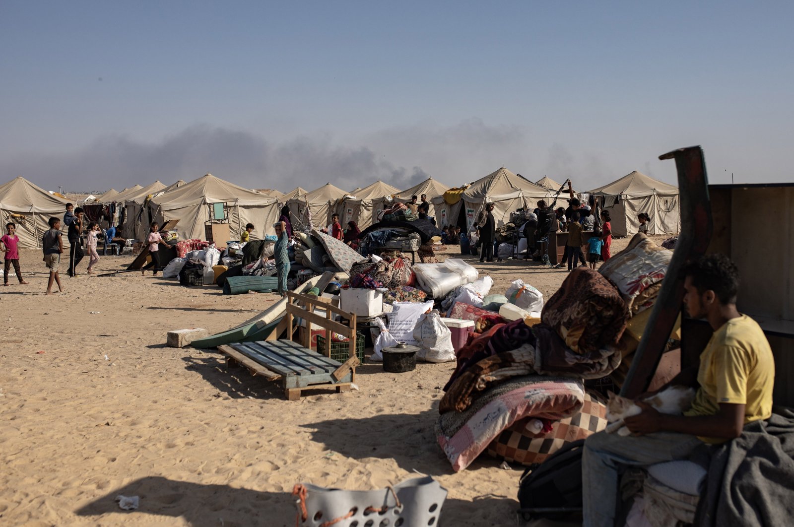 Smoke rises (back) from an airstrike on Rafah, as internally displaced Palestinians (front) prepare to evacuate the al-Mawasi area after Israeli army vehicles advanced, Rafah, Gaza Strip, Palestine, June 4, 2024. (EPA Photo)