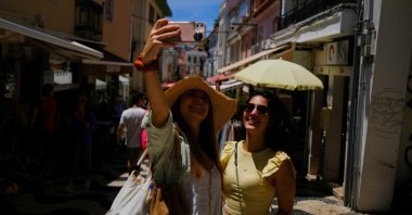 Tourists take a picture on a street in Cascais, Portugal, June 6, 2022. (Reuters Photo)