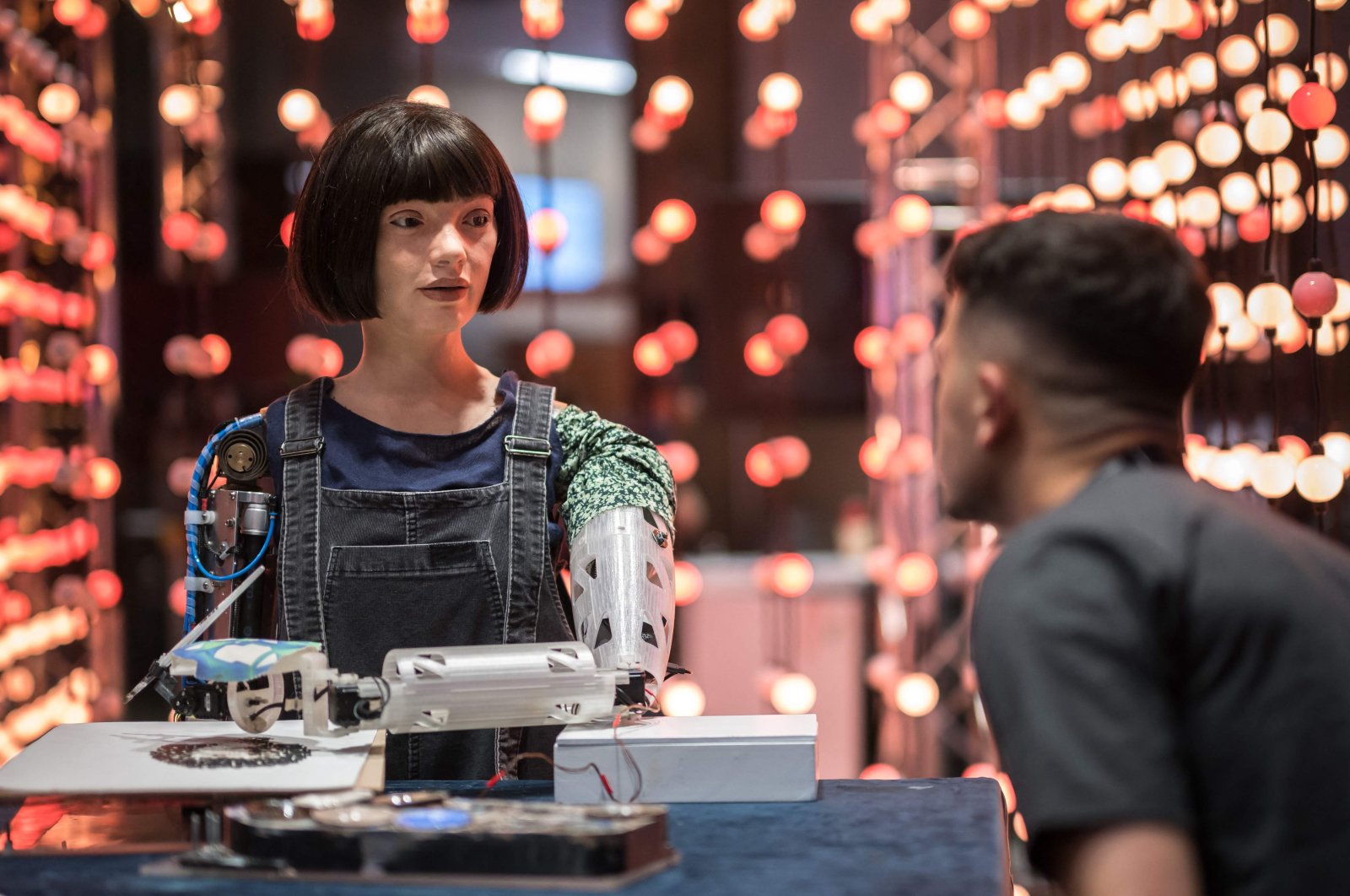 A man faces the realistic artist robot &quot;Ai-Da&quot; using artificial intelligence at a stand during the International Telecommunication Union (ITU) AI for Good Global Summit, Geneva, Switzerland, May 30, 2024. (AFP Photo)