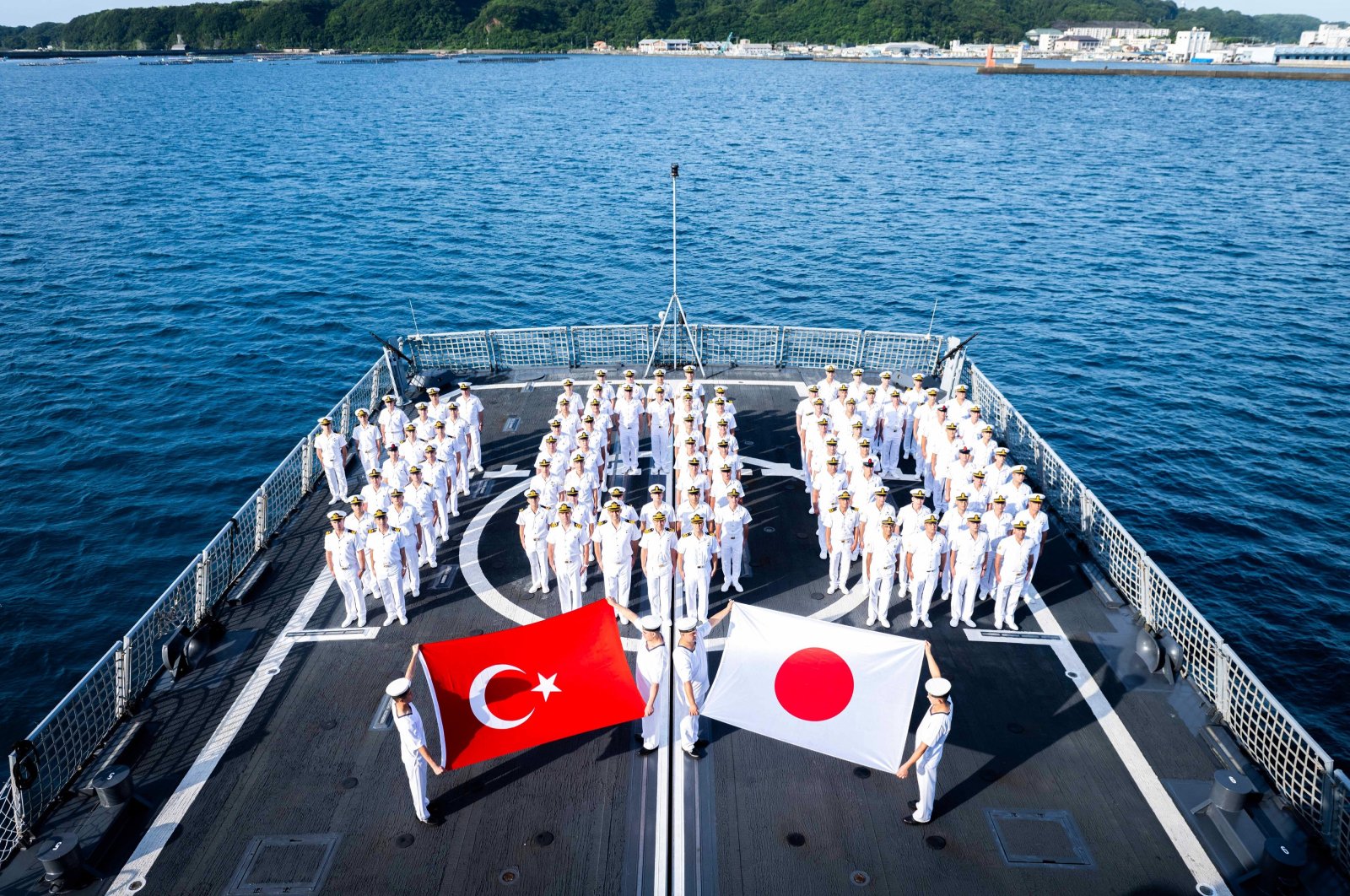 The crew of TCG Kınalıada holds Turkish and Japanese flags, off the coast of Kushimoto, Japan, June 8, 2024. (AA Photo)