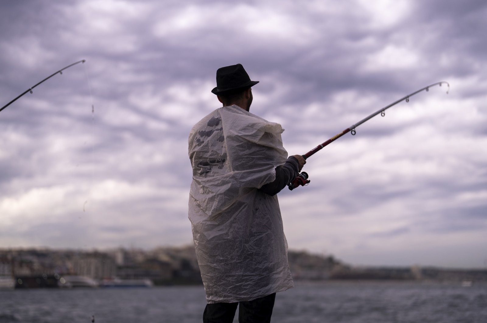 A man casts his line into the Bosporus during a spring rain in Istanbul, Türkiye, May 23, 2024. (AP Photo)