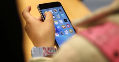 A child holds an iPhone at an Apple store in Chicago, U.S., Sept. 25, 2015. (AP Photo)