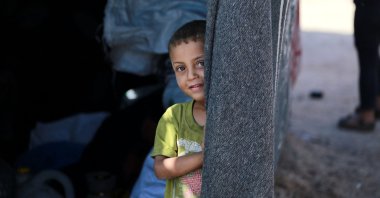A Palestinian boy peeps from inside a tent at a camp for displaced people in Deir al-Balah, in the central Gaza Strip, Palestine, June 11, 2024. (AFP Photo)