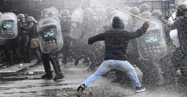 A demonstrator clashes with riot police while sprayed from a police water cannon outside the National Congress in Buenos Aires, Argentina, June 12, 2024. (AFP Photo)