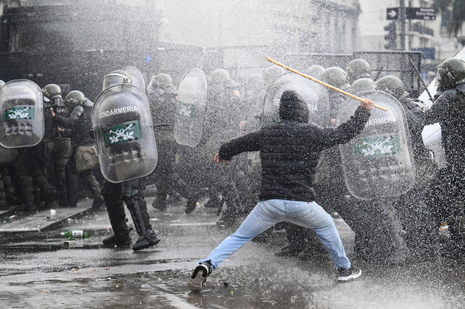 A demonstrator clashes with riot police while sprayed from a police water cannon outside the National Congress in Buenos Aires, Argentina, June 12, 2024. (AFP Photo)