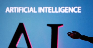 Artificial Intelligence letters and robot hand miniature are seen in this illustration taken on June 23, 2023. (Reuters Photo)