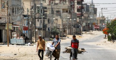 A man pulls a cart loaded with salvaged wood alongside another pushing a bicycle loaded with bags along a street in the eastern part of Rafah in the southern Gaza Strip, Palestine, June 14, 2024. (AFP Photo)