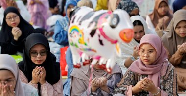 An inflatable toy depicting a cow is seen as Muslims attend morning mass prayers during Eid al-Adha celebrations, Jakarta, Indonesia, June 17, 2024. (Reuters Photo)