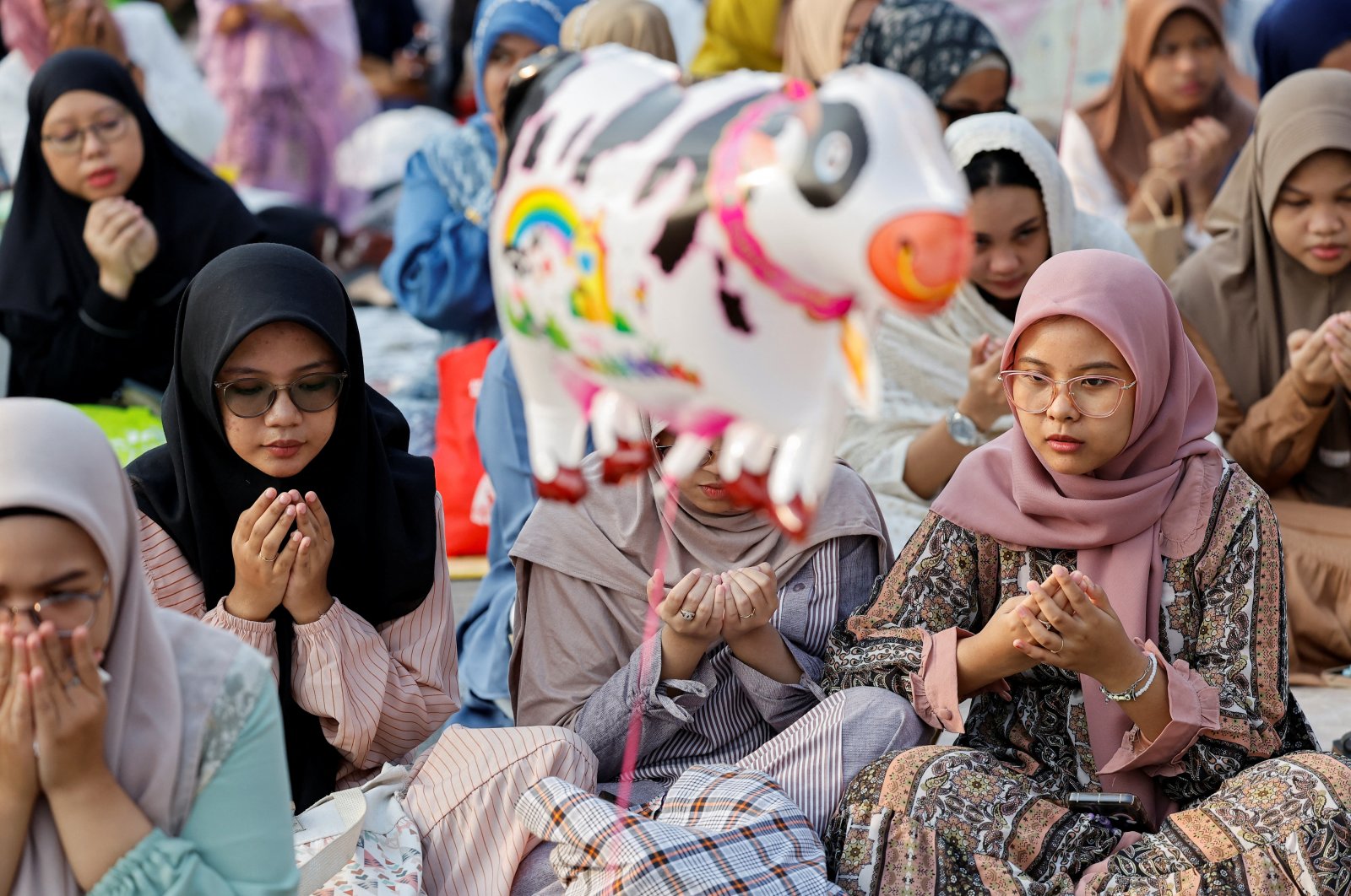 An inflatable toy depicting a cow is seen as Muslims attend morning mass prayers during Eid al-Adha celebrations, Jakarta, Indonesia, June 17, 2024. (Reuters Photo)