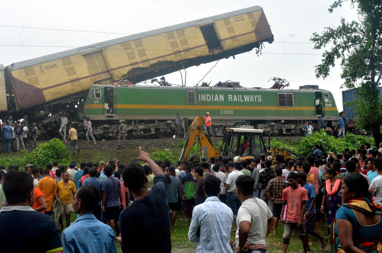 Onlookers watch as National Disaster Response Force (NDRF) rescuers work at the site of a train collision, near Rangapani station, West Bengal state, India, June 17, 2024. (EPA Photo)