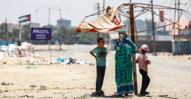 A woman stands with two children under a fraying shade along a street in the western part of Rafah in the southern Gaza Strip, Palestine, June 14, 2024. (AFP Photo)