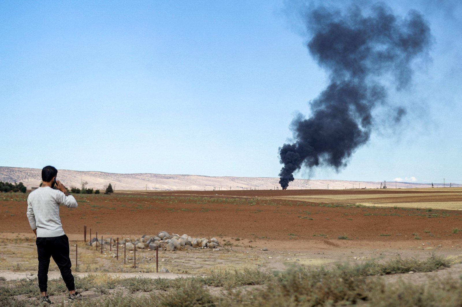 A man watches from afar as a fire rages after a Turkish airstrike at the Zarba oil facility occupied by the PKK/YPG terrorist group, al-Qahtaniyah, Syria, Oct. 5, 2023. (AFP Photo)