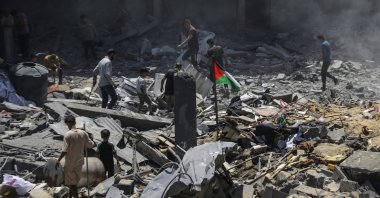 A Palestinian flag flies among the rubble as people inspect the damage following an Israeli airstrike at al-Bureij refugee camp, southern Gaza Strip, Palestine, June 18, 2024. (EPA Photo)